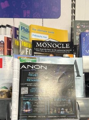 Crypto Magazine on a UK newsstand shelf with the ANON NFTs ad facing out, beside Monocle